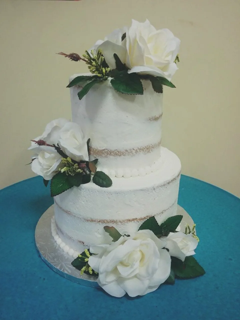 Two-tier naked cake decorated with white roses