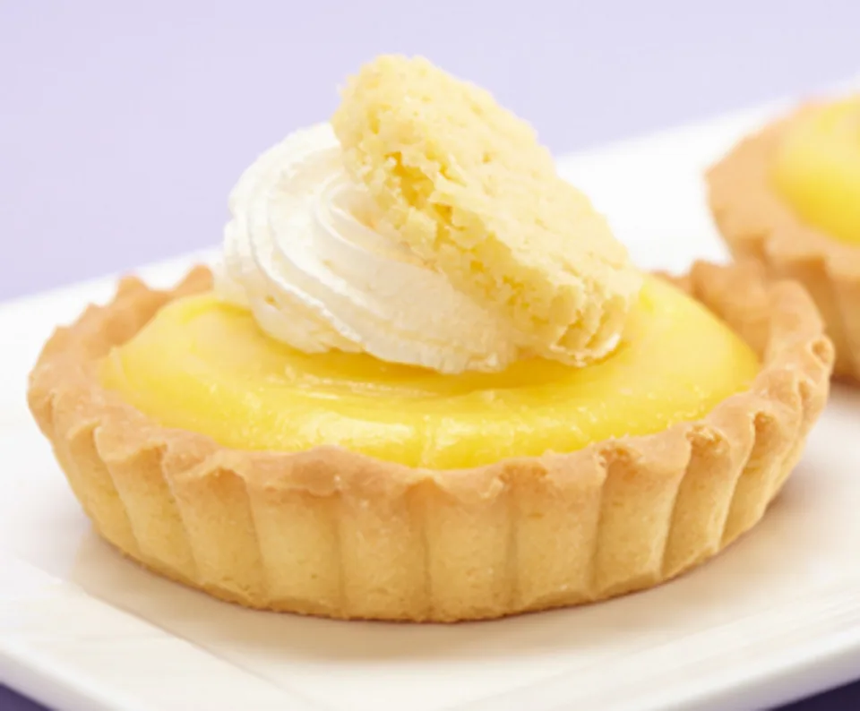 Lemon tart topped with whipped cream and a slice of lemon