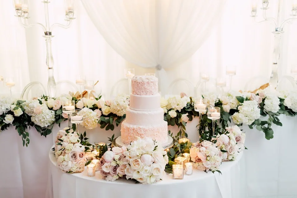 Wedding sweet table with a tiered cake, cupcakes and flowers